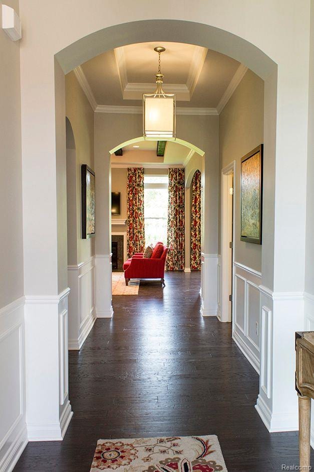 14268 Durant St, Fenton, MI 48451 - corridor featuring dark wood-style flooring, a tray ceiling, wainscoting, crown molding, and a decorative wall