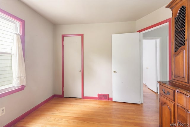 630 Symes Ave, Royal Oak, MI 48067 - unfurnished bedroom with multiple windows, light wood-style floors, and baseboards