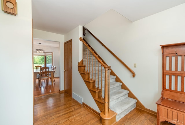 3677 W White Trillium Dr, Saginaw, MI 48603 - stairway featuring wood finished floors, a chandelier, and baseboards
