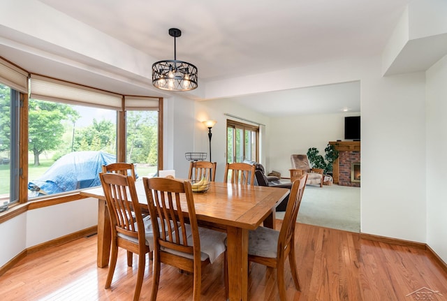 3677 W White Trillium Dr, Saginaw, MI 48603 - dining space with a chandelier, a brick fireplace, baseboards, and light wood finished floors