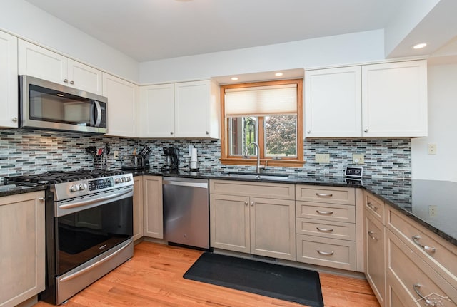 3677 W White Trillium Dr, Saginaw, MI 48603 - kitchen featuring stainless steel appliances, a sink, light wood-type flooring, dark stone counters, and recessed lighting