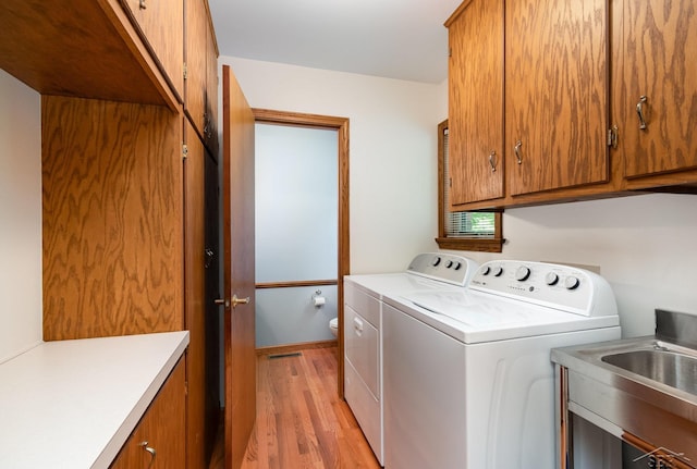 3677 W White Trillium Dr, Saginaw, MI 48603 - washroom with cabinet space, separate washer and dryer, and light wood-style flooring