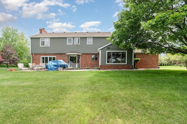 3677 W White Trillium Dr, Saginaw, MI 48603 - rear view of property with a chimney, a lawn, brick siding, and a patio area
