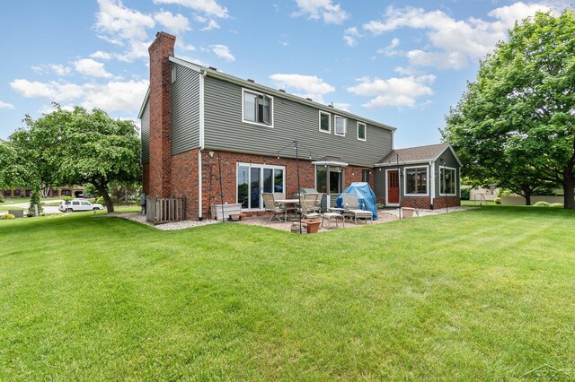 3677 W White Trillium Dr, Saginaw, MI 48603 - rear view of house featuring a chimney, a patio area, brick siding, and a yard