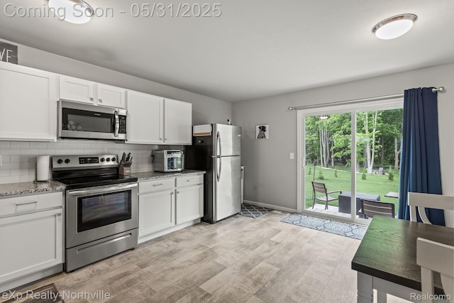 342 Lotz Ct, Wayland, MI 49348 - kitchen with appliances with stainless steel finishes, light wood-style flooring, white cabinets, tasteful backsplash, and light stone countertops