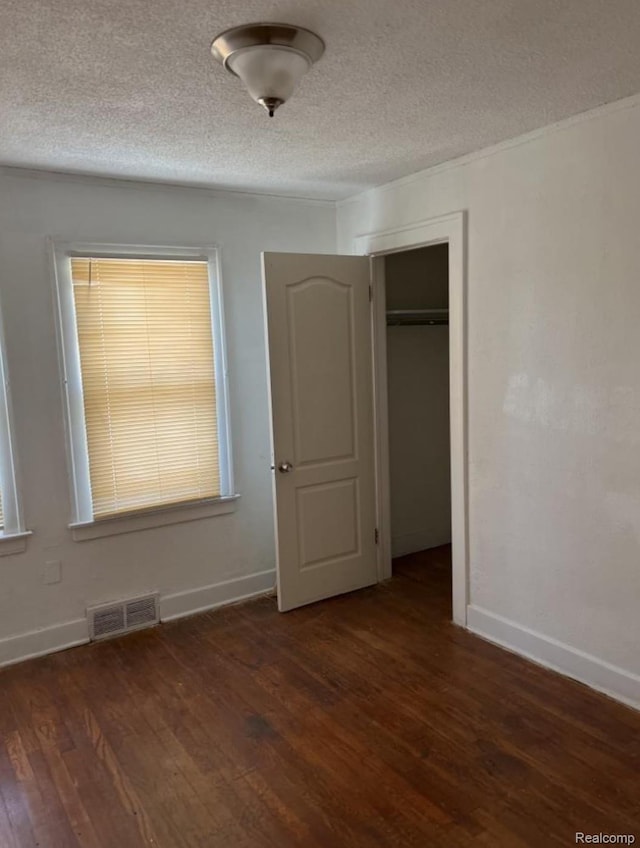 18542 Dale St, Detroit, MI 48219 - unfurnished bedroom featuring wood finished floors, baseboards, a textured ceiling, a closet, and multiple windows