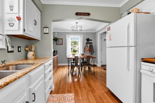 3822 Polk St, Dearborn, MI 48124 - kitchen featuring freestanding refrigerator, a sink, white cabinets, light wood-type flooring, and a chandelier