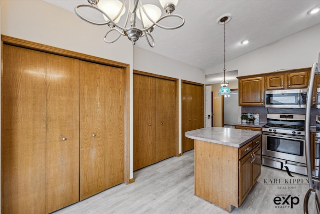 310 Timber Creek Cir NW, Comstock Park, MI 49321 - kitchen with stainless steel appliances, a kitchen island, light wood finished floors, a chandelier, and pendant lighting