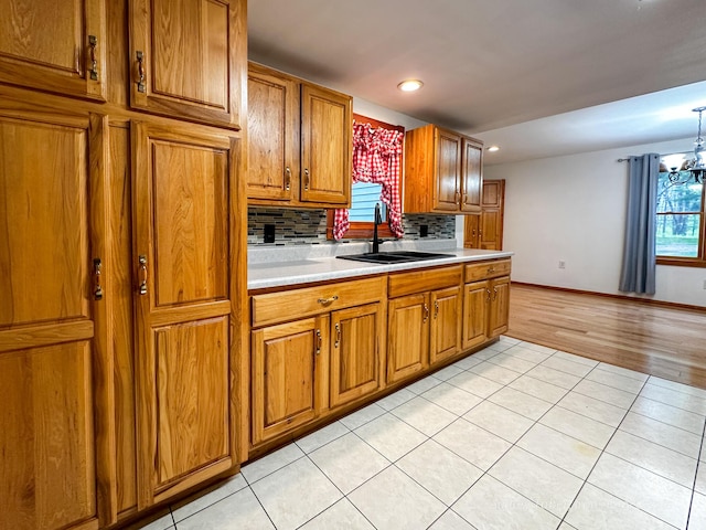 4307 N Mac Rd, Irons, MI 49644 - kitchen featuring brown cabinetry, light countertops, decorative backsplash, light tile patterned flooring, and a chandelier
