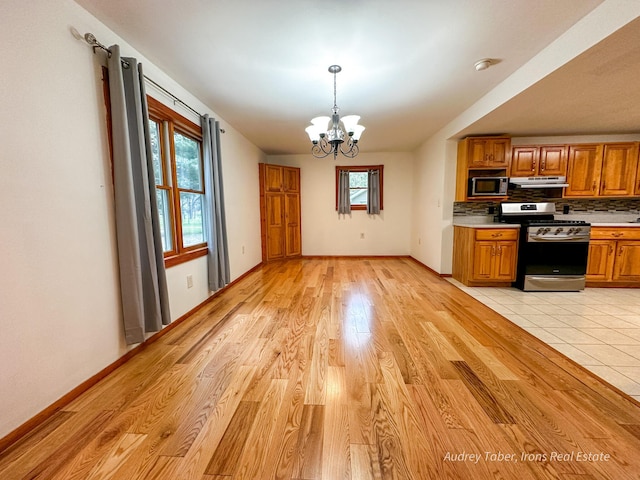 4307 N Mac Rd, Irons, MI 49644 - kitchen with appliances with stainless steel finishes, a chandelier, light countertops, brown cabinets, and decorative backsplash