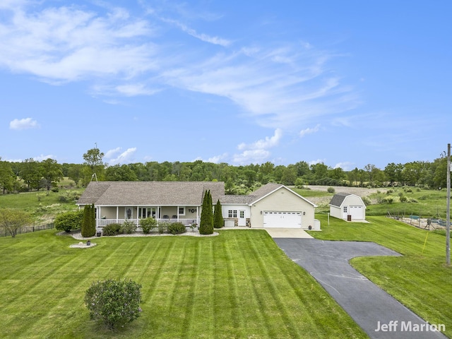 2057 Nickleplate Rd, Ionia, MI 48846 - ranch-style house with asphalt driveway, an attached garage, a porch, a front yard, and view of scattered trees