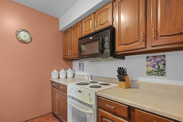 3272 Cambridge St SE, Grand Rapids, MI 49512 - kitchen featuring white range with electric stovetop, black microwave, light countertops, and brown cabinetry