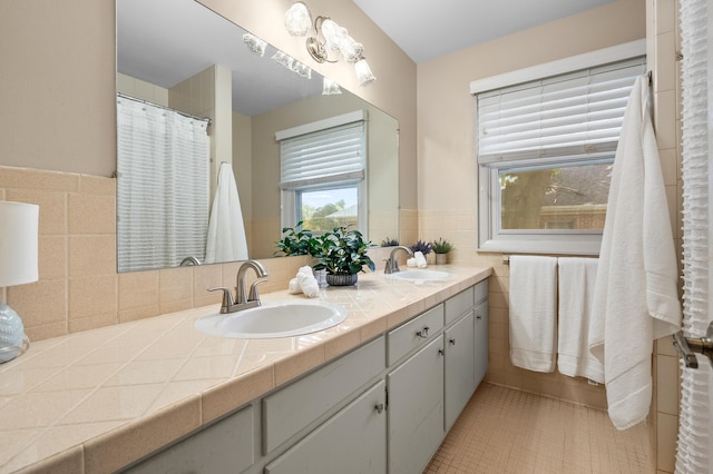 313 W Kilgore Rd, Portage, MI 49002 - bathroom with double vanity, tile walls, wainscoting, and tile patterned floors