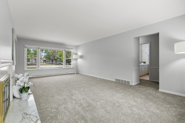 313 W Kilgore Rd, Portage, MI 49002 - unfurnished living room featuring baseboard heating, baseboards, and carpet