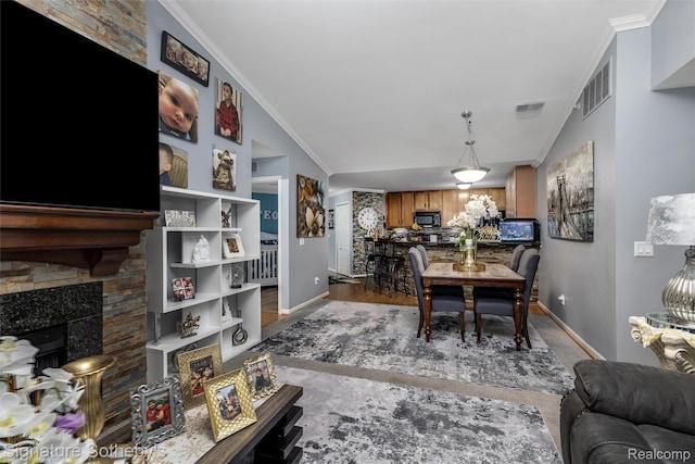 340 N Wixom Rd, Wixom, MI 48393 - dining space with baseboards, lofted ceiling, wood finished floors, crown molding, and a fireplace