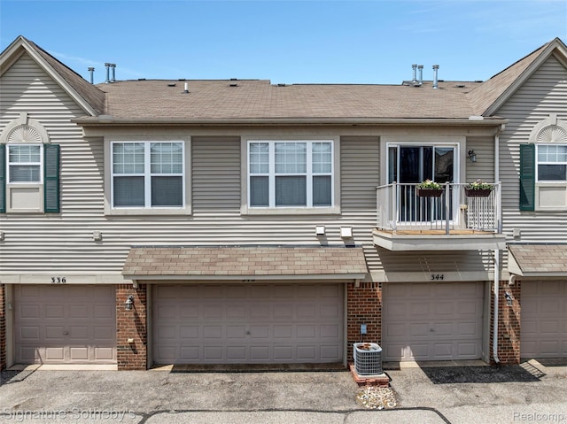 340 N Wixom Rd, Wixom, MI 48393 - rear view of property with brick siding, an attached garage, and a balcony