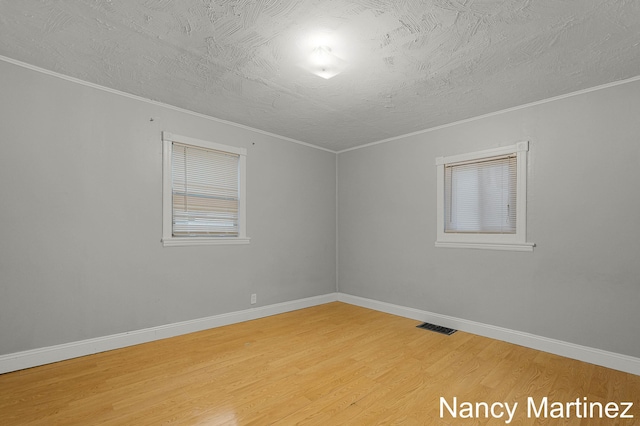 853 California St NW, Grand Rapids, MI 49504 - empty room featuring light wood-type flooring, crown molding, baseboards, and a textured ceiling