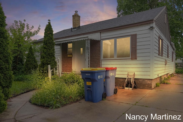 853 California St NW, Grand Rapids, MI 49504 - bungalow-style home featuring a chimney, a patio, a shingled roof, and brick siding