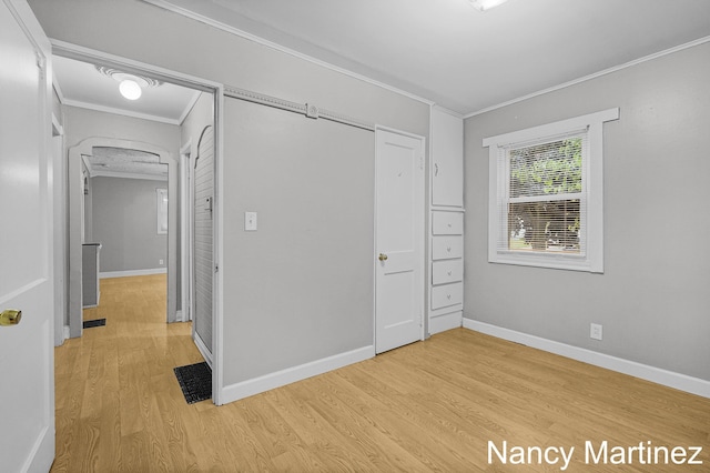 853 California St NW, Grand Rapids, MI 49504 - unfurnished bedroom featuring ornamental molding, light wood-style flooring, arched walkways, and baseboards