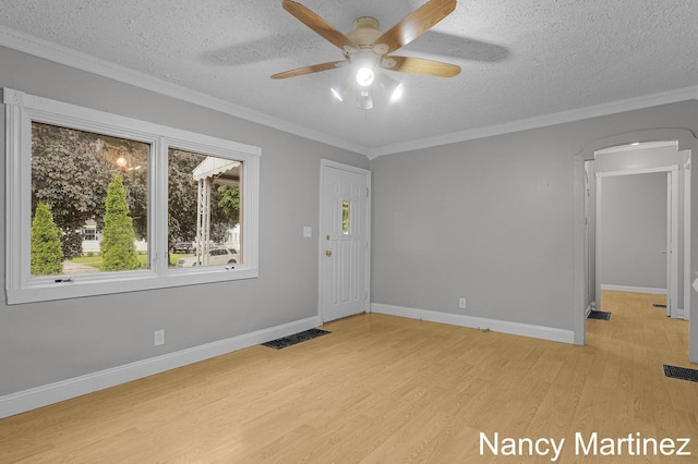 853 California St NW, Grand Rapids, MI 49504 - empty room featuring a textured ceiling, light wood-type flooring, a ceiling fan, baseboards, and arched walkways