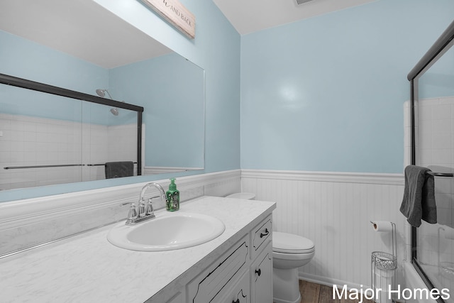 1724 Sandra St NW, Grand Rapids, MI 49544 - full bathroom featuring toilet, a shower with shower door, vanity, wainscoting, and wood finished floors