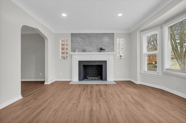17217 Plainview Ave, Detroit, MI 48219 - unfurnished living room with wood finished floors, baseboards, a large fireplace, recessed lighting, and arched walkways