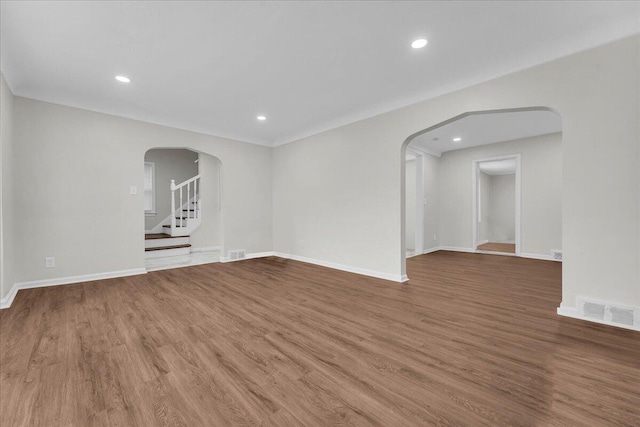 17217 Plainview Ave, Detroit, MI 48219 - spare room featuring arched walkways, wood finished floors, baseboards, recessed lighting, and stairway