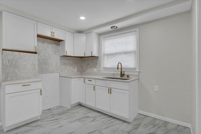 17217 Plainview Ave, Detroit, MI 48219 - kitchen featuring light marble finish flooring, a sink, white cabinetry, light countertops, and decorative backsplash