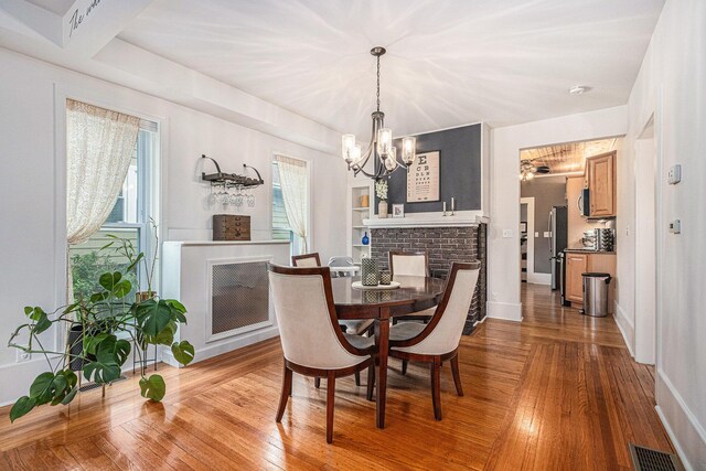 2335 Niles Ave, Saint Joseph, MI 49085 - dining room featuring a chandelier, hardwood / wood-style floors, a brick fireplace, and baseboards