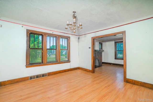 12151 Corbett St, Detroit, MI 48213 - empty room featuring wood finished floors, a textured ceiling, and a chandelier