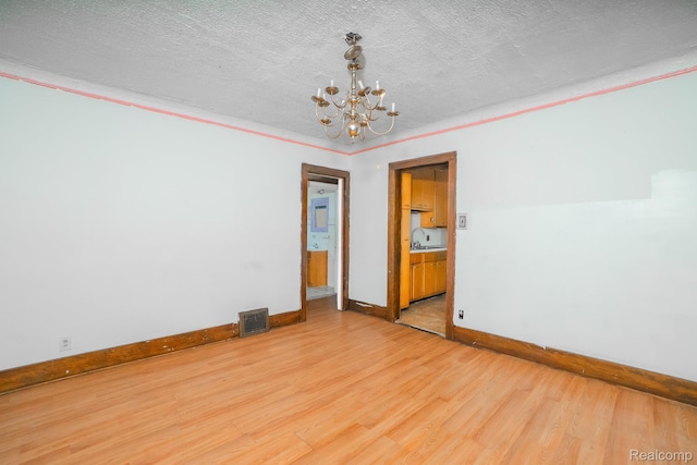 12151 Corbett St, Detroit, MI 48213 - unfurnished room featuring a chandelier, light wood-style floors, a textured ceiling, and ornamental molding