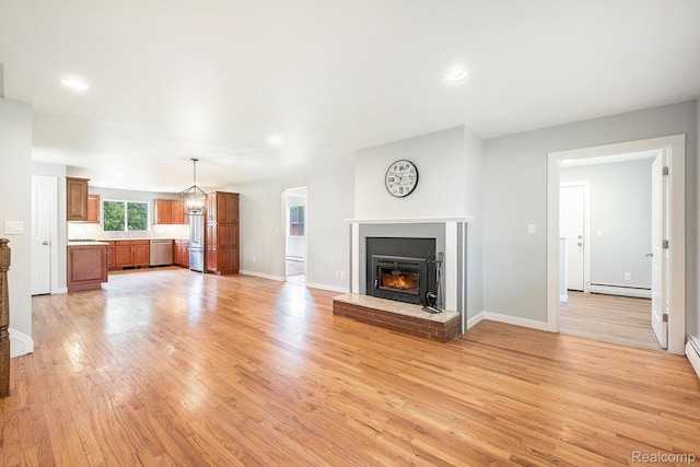 7340 Hartland Rd, Fenton, MI 48430 - unfurnished living room featuring baseboard heating, light wood-style flooring, a brick fireplace, recessed lighting, and baseboards