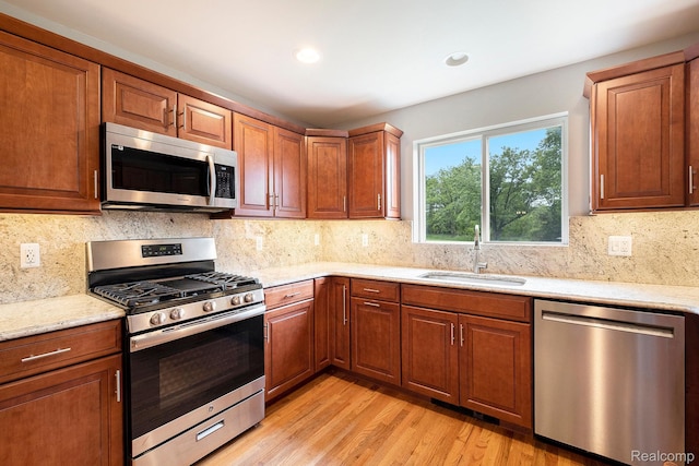 7340 Hartland Rd, Fenton, MI 48430 - kitchen with stainless steel appliances, a sink, light wood-style floors, tasteful backsplash, and light stone counters