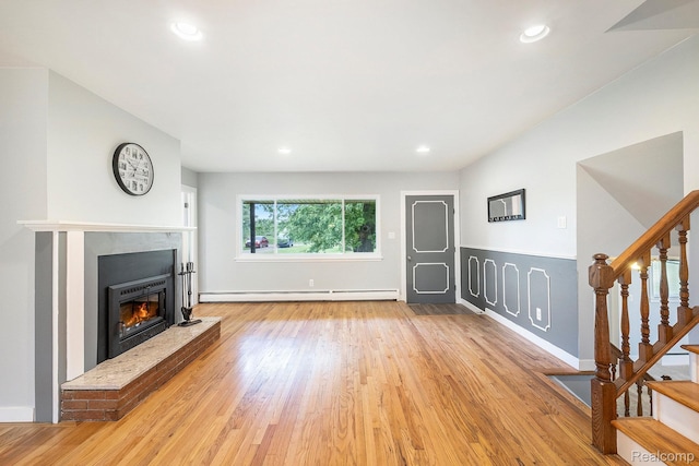 7340 Hartland Rd, Fenton, MI 48430 - unfurnished living room featuring stairs, wood finished floors, a glass covered fireplace, a baseboard heating unit, and recessed lighting
