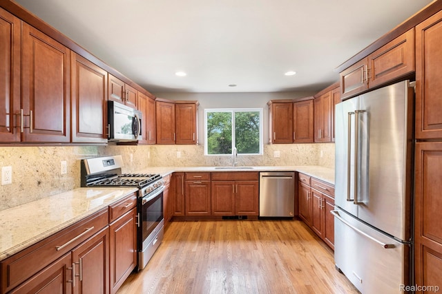 7340 Hartland Rd, Fenton, MI 48430 - kitchen featuring stainless steel appliances, a sink, light wood-style floors, brown cabinetry, and recessed lighting