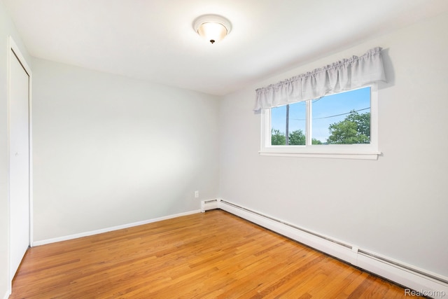 7340 Hartland Rd, Fenton, MI 48430 - unfurnished bedroom with a baseboard heating unit, light wood finished floors, a closet, and baseboards