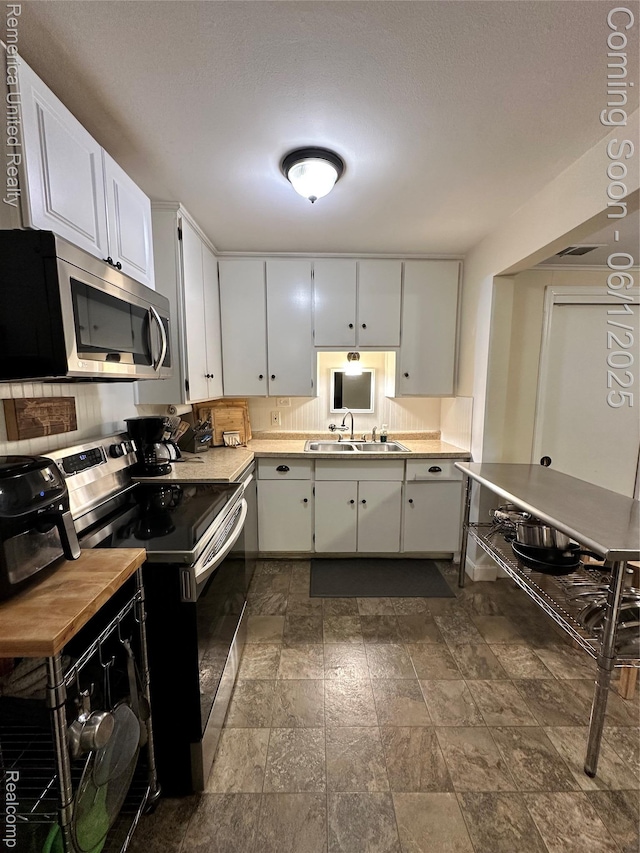 9044 N Sheldon Rd, Plymouth, MI 48170 - kitchen featuring stainless steel appliances, a sink, white cabinets, stone finish flooring, and light countertops