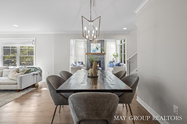 2050 Anderson Dr SE, East Grand Rapids, MI 49506 - dining room with ornamental molding, a chandelier, baseboards, wood finished floors, and a fireplace