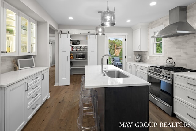 2050 Anderson Dr SE, East Grand Rapids, MI 49506 - kitchen with wall chimney exhaust hood, stainless steel gas range oven, a sink, a barn door, and white cabinetry