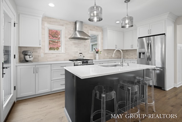2050 Anderson Dr SE, East Grand Rapids, MI 49506 - kitchen with stainless steel appliances, wall chimney range hood, a sink, light wood-style floors, and decorative backsplash