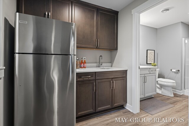 2050 Anderson Dr SE, East Grand Rapids, MI 49506 - kitchen featuring freestanding refrigerator, a sink, light wood-type flooring, light countertops, and dark brown cabinetry