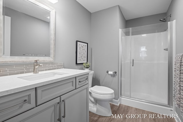 2050 Anderson Dr SE, East Grand Rapids, MI 49506 - bathroom featuring wood finished floors, a stall shower, vanity, toilet, and tasteful backsplash