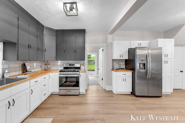 810 James St, Belding, MI 48809 - kitchen with stainless steel appliances, a textured ceiling, wooden counters, light wood-style flooring, and decorative backsplash
