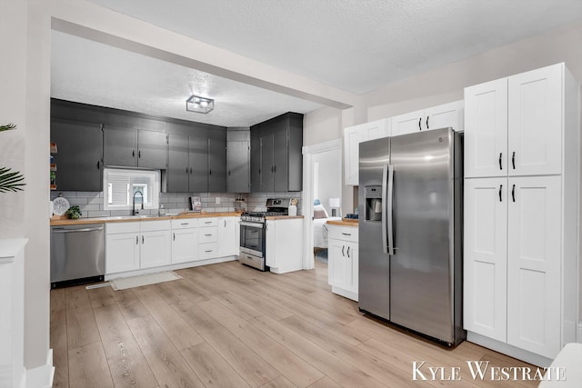 810 James St, Belding, MI 48809 - kitchen with appliances with stainless steel finishes, butcher block countertops, a textured ceiling, backsplash, and white cabinets