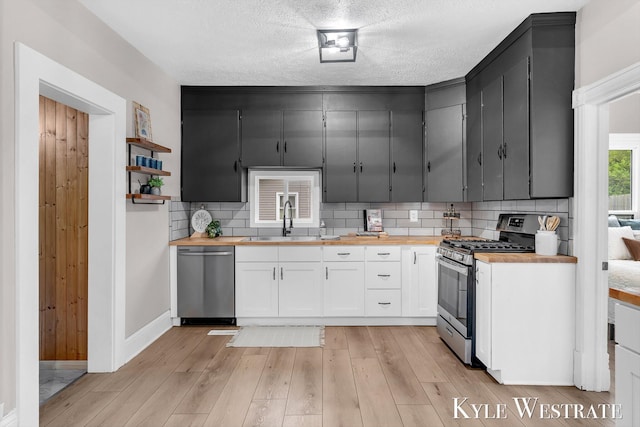 810 James St, Belding, MI 48809 - kitchen with butcher block countertops, stainless steel appliances, a sink, backsplash, and a textured ceiling