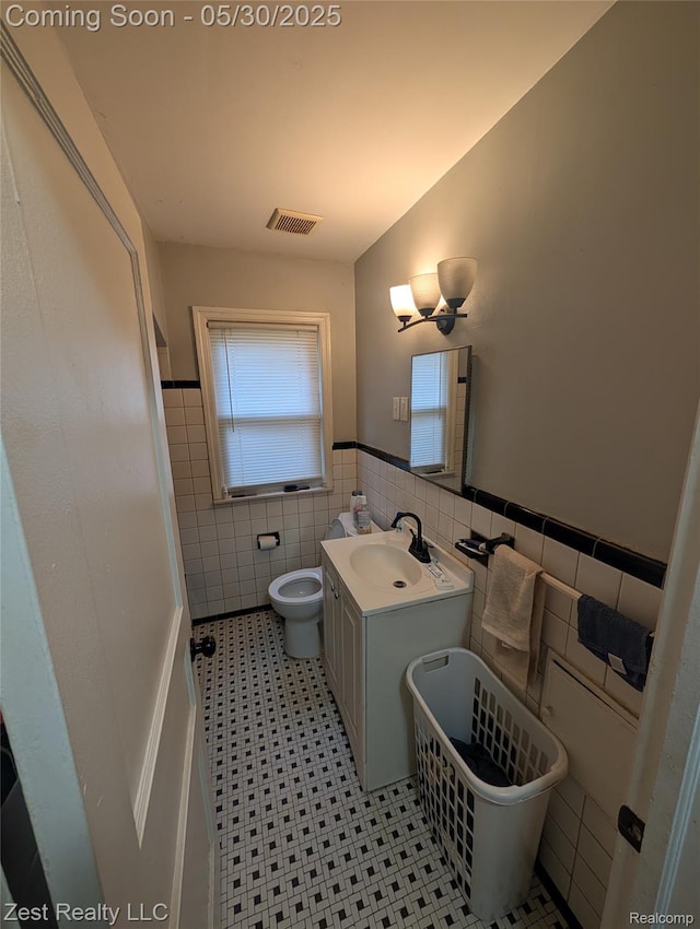15340 Heyden St, Detroit, MI 48223 - bathroom with tile walls, toilet, vanity, a wainscoted wall, and tile patterned floors