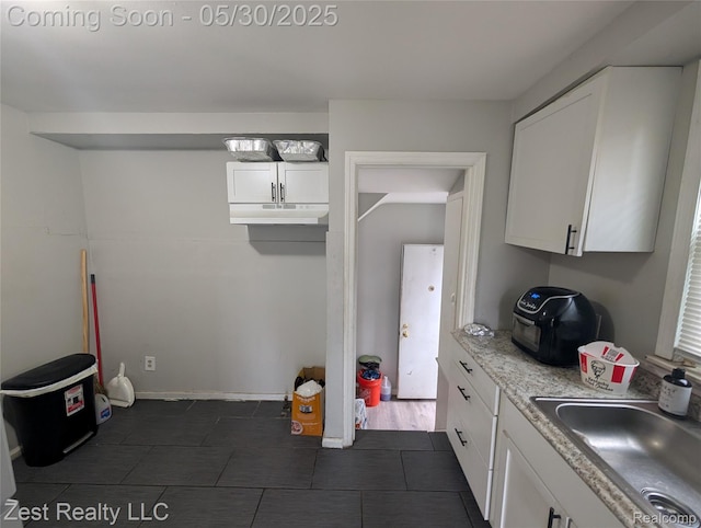 15340 Heyden St, Detroit, MI 48223 - kitchen with a sink, dark tile patterned flooring, white cabinets, light countertops, and under cabinet range hood