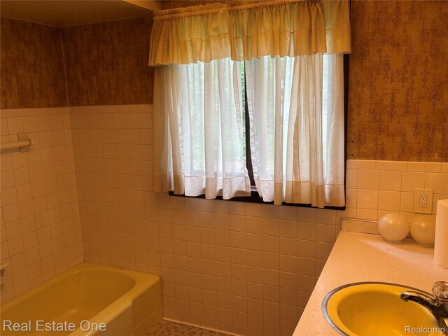 109 W Kennett Rd, Pontiac, MI 48340 - full bath featuring tile walls, wallpapered walls, a bathtub, and wainscoting