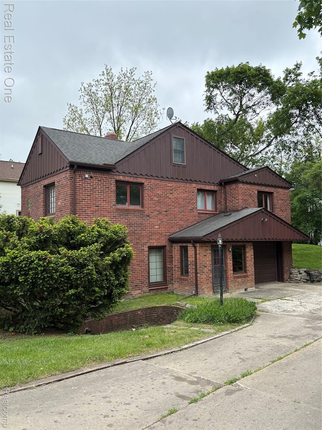 109 W Kennett Rd, Pontiac, MI 48340 - view of front of home with brick siding, board and batten siding, a garage, and concrete driveway