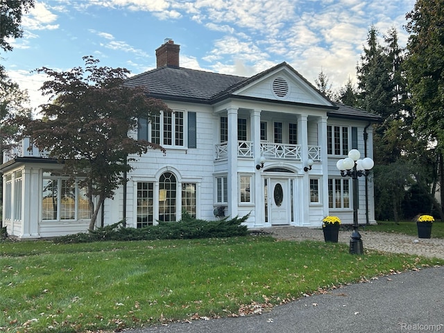 25490 E River Rd, Grosse Ile, MI 48138 - neoclassical / greek revival house featuring a balcony, a chimney, and a front yard